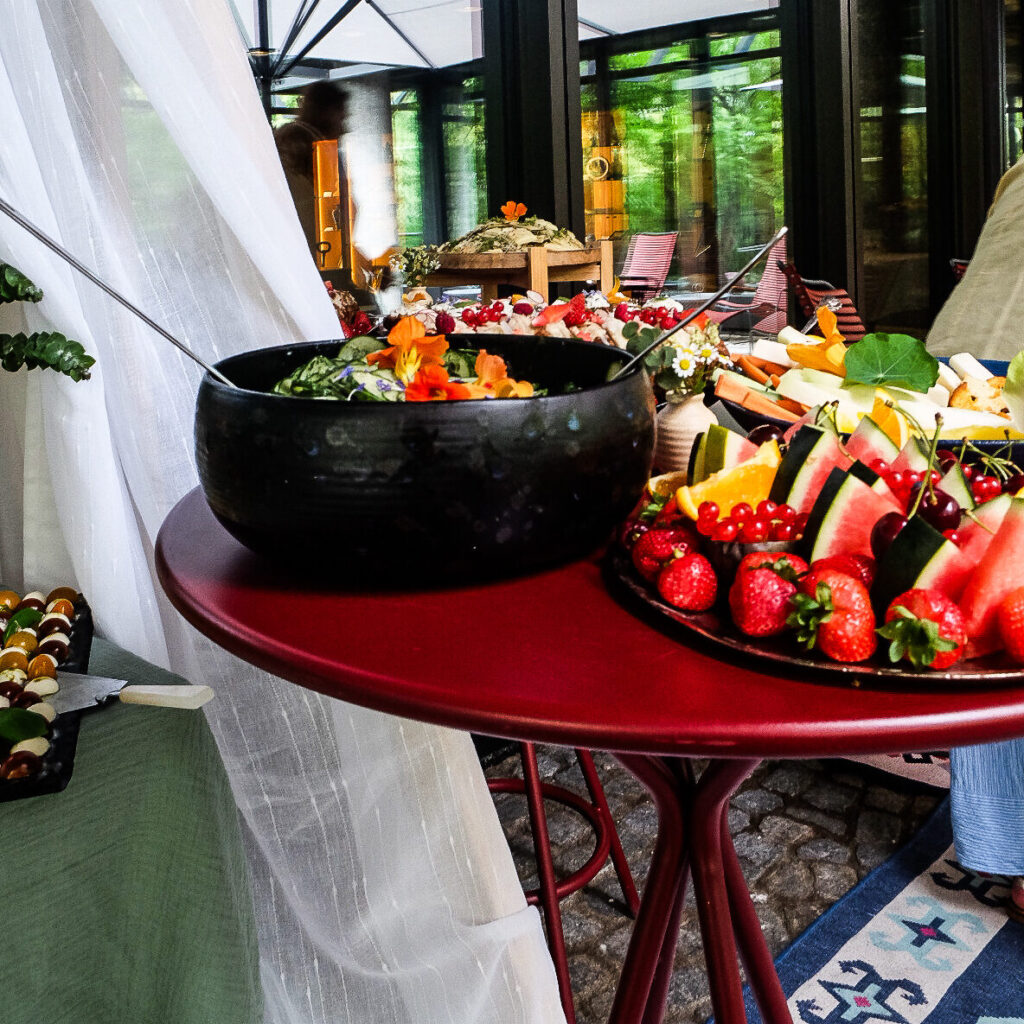 Signature-Picknick-Fotos: „Veganes Signature Picknick von Bananaleaf in einem Münchner Innenhof mit Decken, Kissen und Blumen"